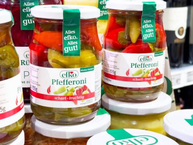 Bir markette rafta sergilenen renkli biber kavanozları, canlı renkler ve çeşitli biber çeşitleri, sağlıklı beslenme konsepti.