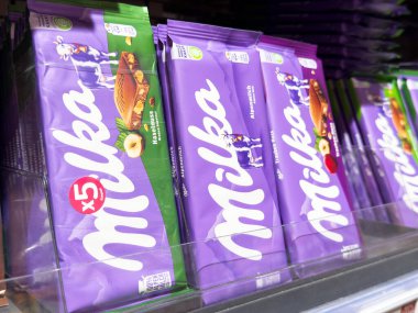 Marketin rafında çeşitli aromalar ve ambalajlar sergilenen Milka çikolataları çikolata severler ve abur cubur sevenler için çekici, çikolata konsepti