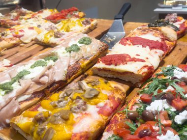 Mantar, prosciutto, peynir, pesto ve ahşap tahtada roka da dahil olmak üzere çeşitli lezzetli gurme pizzalar..