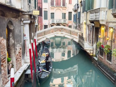 Genç Asyalı gondolcuyla taş köprünün altında Venedik kanalı gondolcusu.