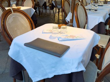 Beyaz masa örtüsü ve tahta sandalyeli açık büfe restoran masası..