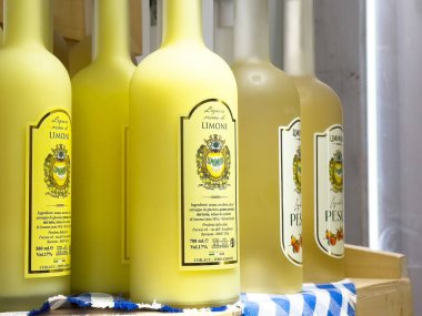 Rafta renkli İtalyan limonu ve şeftali likörü şişeleri.