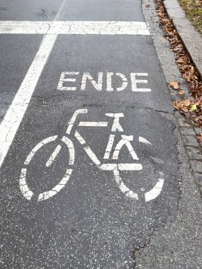 Islak asfalt üzerinde sonbahar yaprakları ile işaretlenen bisiklet yolu sonu.