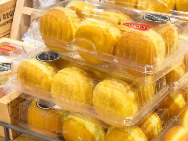 Fırın vitrinindeki plastik ambalajda taze ekmek ruloları yığını.