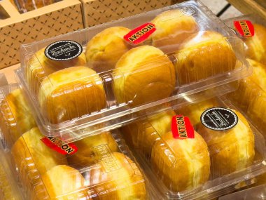 Plastik konteynırda paketlenmiş brioche ekmek ruloları ve fırında satılık etiketler..