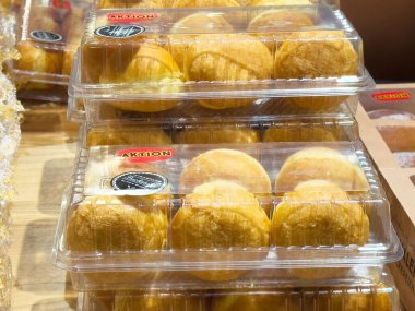 Tahta rafta duran şeffaf plastik kaplarda paketlenmiş çörekler..