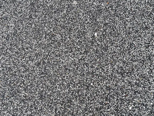 Gri ve beyaz çakıl taşları olan desenli asfalt yüzeyin yakın çekimi.