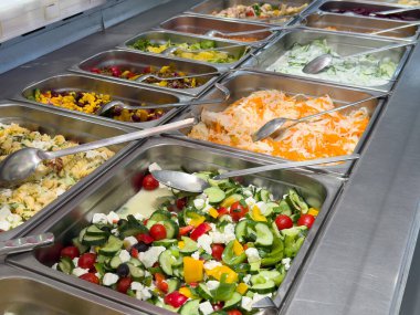 Renkli salata büfesi, taze sebzeler ve paslanmaz çelik tepsilerde peynirler..