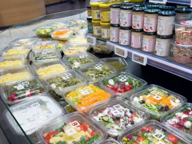 Süpermarkette sergilenen çeşitli taze salata ve baharatlar..