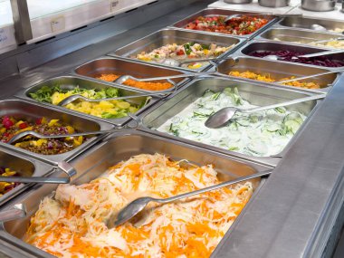 Taze sebzeler ve metal tepsilerde malzemelerle çeşitli salata barı..