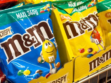 Süpermarketin rafında renkli m & m 'nin fıstık ve çıtır poşetleri.