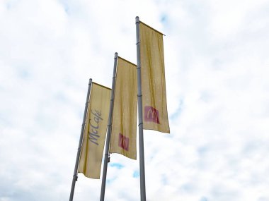 Bulutlu gökyüzüne karşı McDonald 's bayrakları ve McKafe logosu.