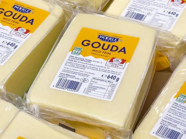 Markette besin etiketleriyle paketlenmiş gouda peyniri blokları görüntülenir.
