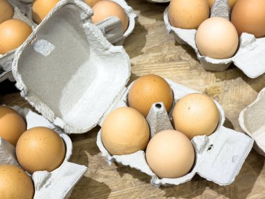 Tahta yüzeydeki açık karton kutularda kahverengi yumurtaların çeşitliliği.