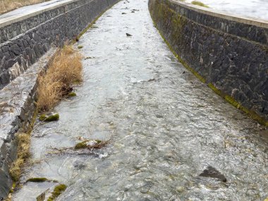 Taştan kanallarda akan yosun ve otlarla.