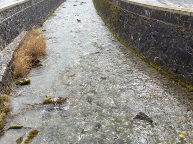 Taş duvarlı kanaldan akan temiz dağ akıntısı.