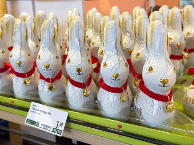 Markette kırmızı kurdeleli ve altın aksanlı çikolatalı tavşanlar sergileniyor.