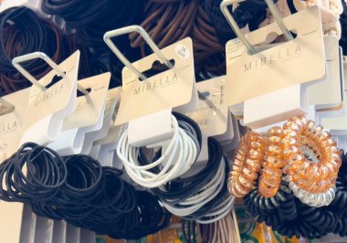 Mağazada çeşitli saç bağları gösteriliyor: siyah, beyaz, metalik renkler.