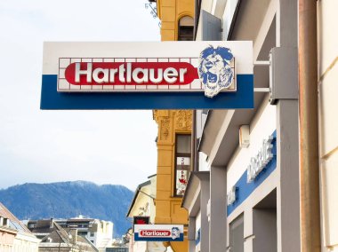 Şehir dağ düzeninde aslan logosu olan Hartlauer mağaza önü tabelası.