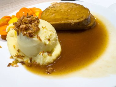 Beyaz tabakta patates püresi, havuç ve sos ile lezzetli bir rulo köfte..