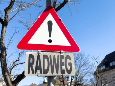 Güneşli bir günde mavi gökyüzü ile Alman bisiklet yolu uyarısı.