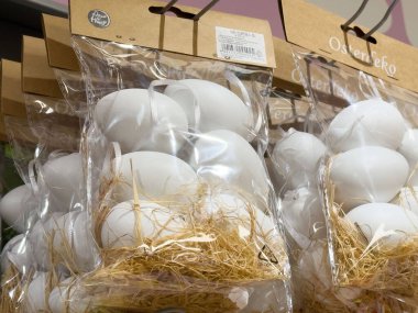 Paketlenmiş beyaz paskalya yumurtaları plastik torbalarda saman yuvası sergileniyor..