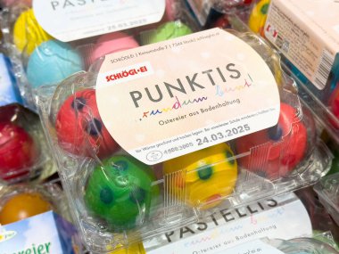 Alman süpermarket vitrininde son kullanma tarihi olan karton paketlerde renkli paskalya yumurtaları.