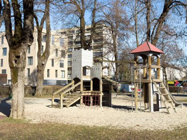 Şato temalı yapıları ve ağaçları olan güneşli şehir oyun alanı.