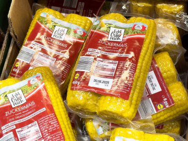 Pazar ortamında satılık kırmızı ve yeşil etiketli paketlenmiş mısır başakları.