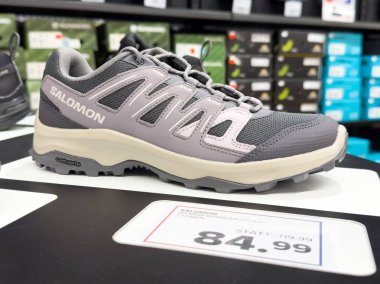 Mağaza ayarlarında indirimli fiyat etiketi olan gri yürüyüş ayakkabıları sergileniyor.