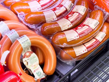 Süpermarketin soğutmalı bölümünde sergilenen paketlenmiş sosislerin çeşitliliği.
