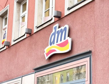 Pembe bina duvarında logo olan Dm mağaza penceresi.