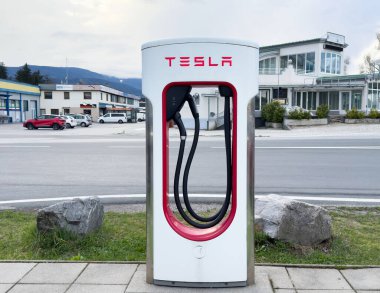 Tesla bulutlu bir günde arka plan manzaralı açık hava şarj istasyonu.