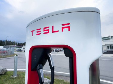 Bulutlu bir günde açık havada çift şarj kabloları olan Tesla süperşarj istasyonu..