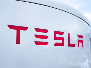 Tesla logosunun elektrikli araç şarj istasyonuna yakın plan görüntüsü.