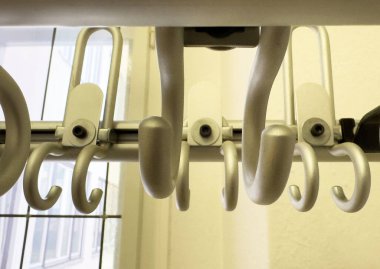 Metalik giysiler pencere manzaralı güneşli odada demiryoluna asılıyor..