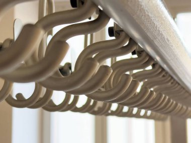 Bej perdelerin yakın plan kancaları yumuşak ışıkta oltaya takılır.