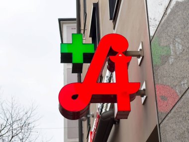 Şehir binasının ön cephesinde yeşil haçlı kırmızı eczane işareti.