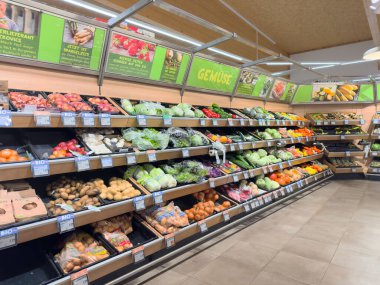 Süpermarket koridorunda sebze ve meyve raflarında taze ürün sergileniyor..