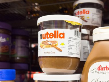 Nutella kavanozları etiketleri ve ambalaj detaylarıyla dolu raflarda saklanır.