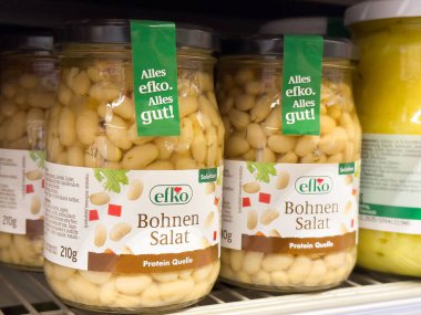 Rafta bohnen salatası kavanozları ve bağırsak etiketleri var..