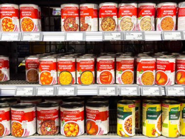 Süpermarket raflarında çeşitli konserve yiyecekler sergileniyor.