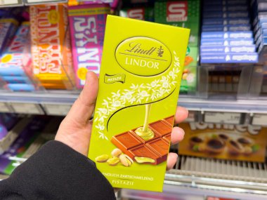 Fıstıklı Lindt çikolatası. Beyaz yetişkin tarafından şeker reyonunda tutuluyor..
