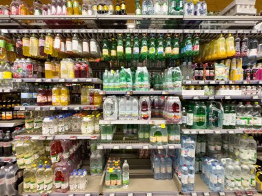 Raflarda çeşitli su ve meşrubat şişeleri olan süpermarket içecek reyonu.