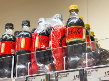 Market raflarında çeşitli Coca-Cola şişeleri sergilenmektedir..