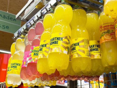 Süpermarket koridorundaki raflarda renkli şişelenmiş içecekler.