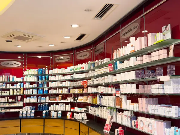 Geniş kırmızı eczane, çeşitli ilaç ve cilt ürünleri sergiliyor..