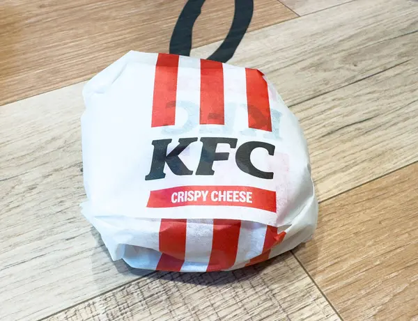 KFC çıtır çıtır peynirli sandviç. Ahşap masaya damgalanmış kırmızı ve beyaz kağıt..
