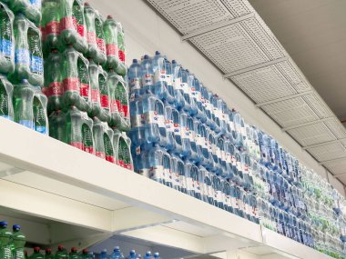 Süpermarket raflarında istiflenmiş plastik su şişeleri.