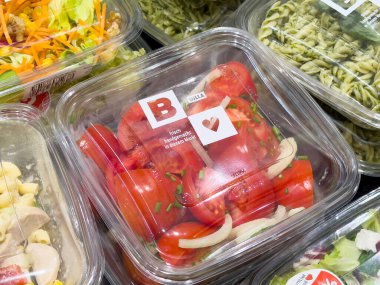 Pazar vitrininde plastik kabın içinde taze kırmızı biber ve soğan..